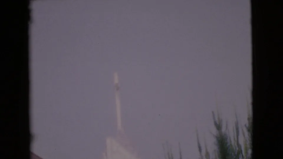 A pale church steeple appears against a hazy sky in 1968 San Diego County 8mm footage.