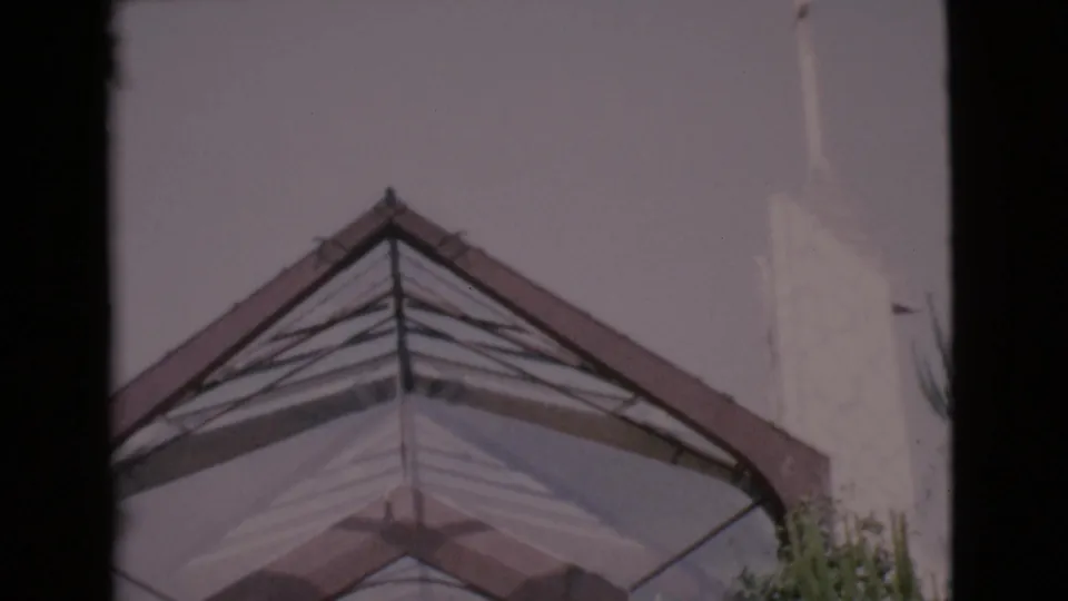 The final 1968 San Diego County frame centers the triangular roofline and pale church steeple from a low angle.