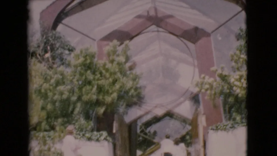 1968 San Diego County frame showing adults near broad steps below a modern glass-and-steel entrance.