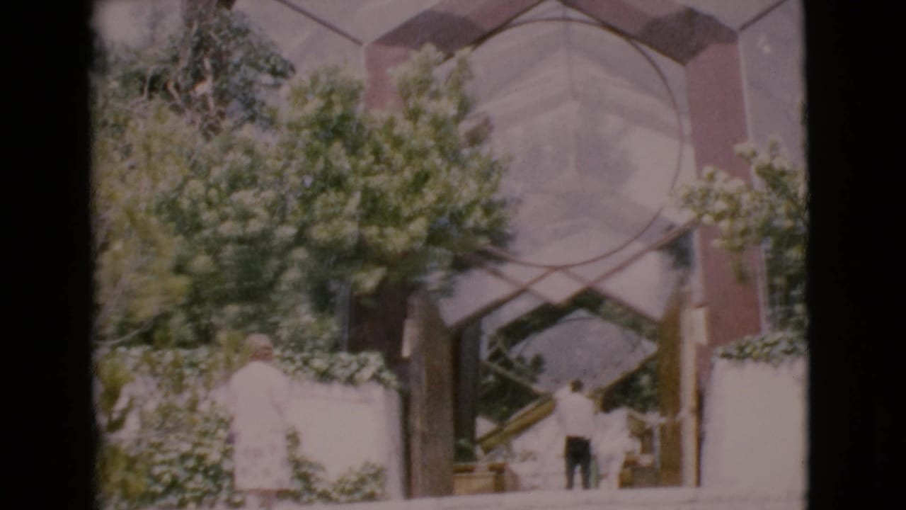Man walking down steps as a woman stands nearby at a modern building entrance.