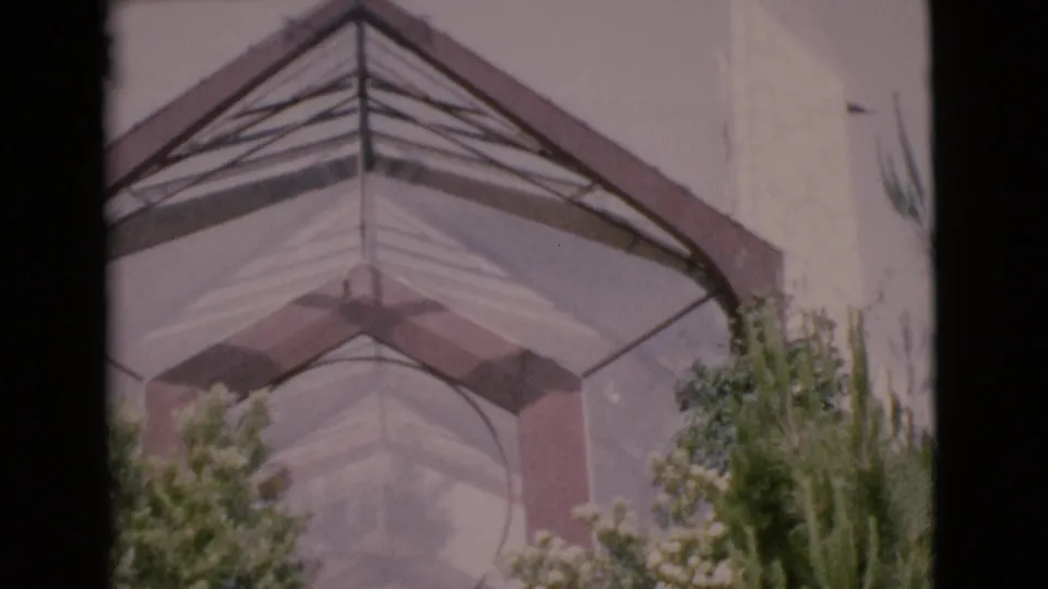 A close 1968 home-movie view of the building's peaked geometric roof, pale wall surfaces, and surrounding plantings.