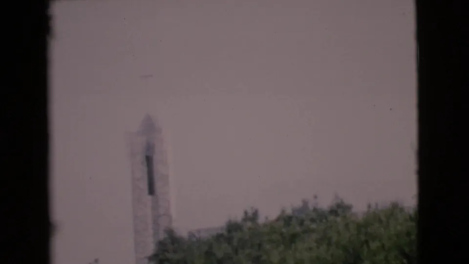 A distant white steeple or tower rises above green trees in a hazy 1968 San Diego County 8mm frame.