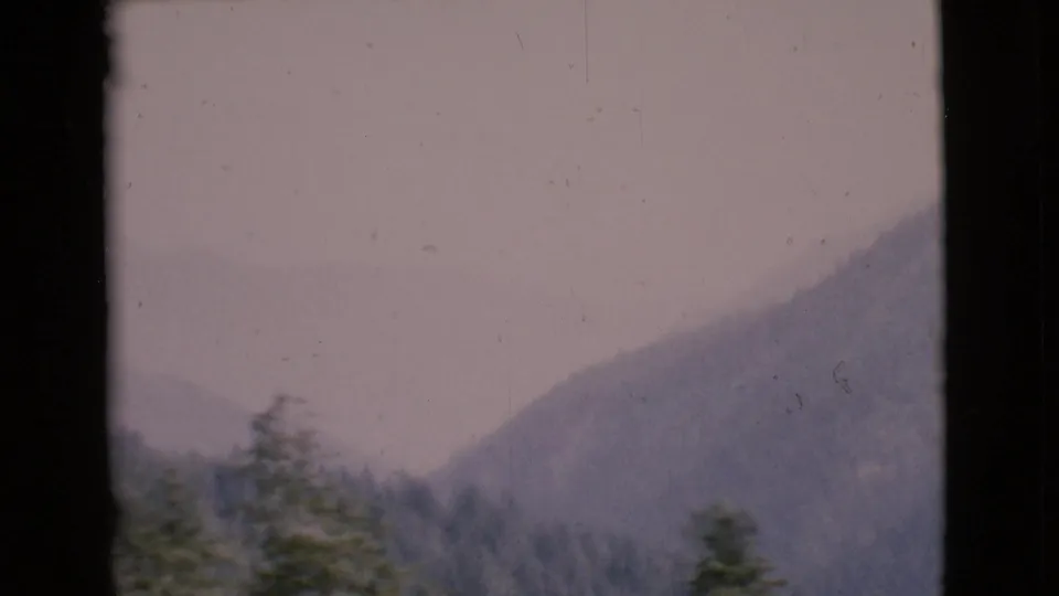 Final 1968 8mm frame shifts from the sign to a soft view of trees and a mountain slope near the chapel setting.
