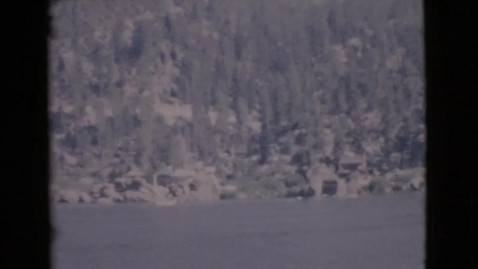 1968 8mm frame of a calm lake and distant wooded shoreline in the supplied San Diego County home-movie metadata.