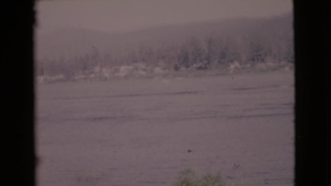 Calm water and a hazy distant shoreline seen between dark vertical frame edges.