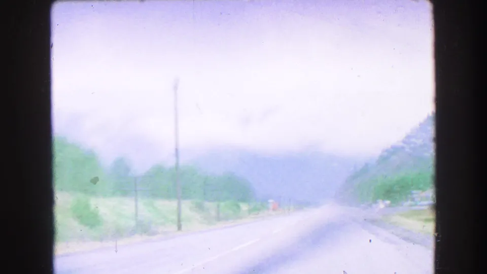 1968 8mm travel footage shows a hazy mountain road near Vancouver with telephone poles, slopes, and soft exposure.