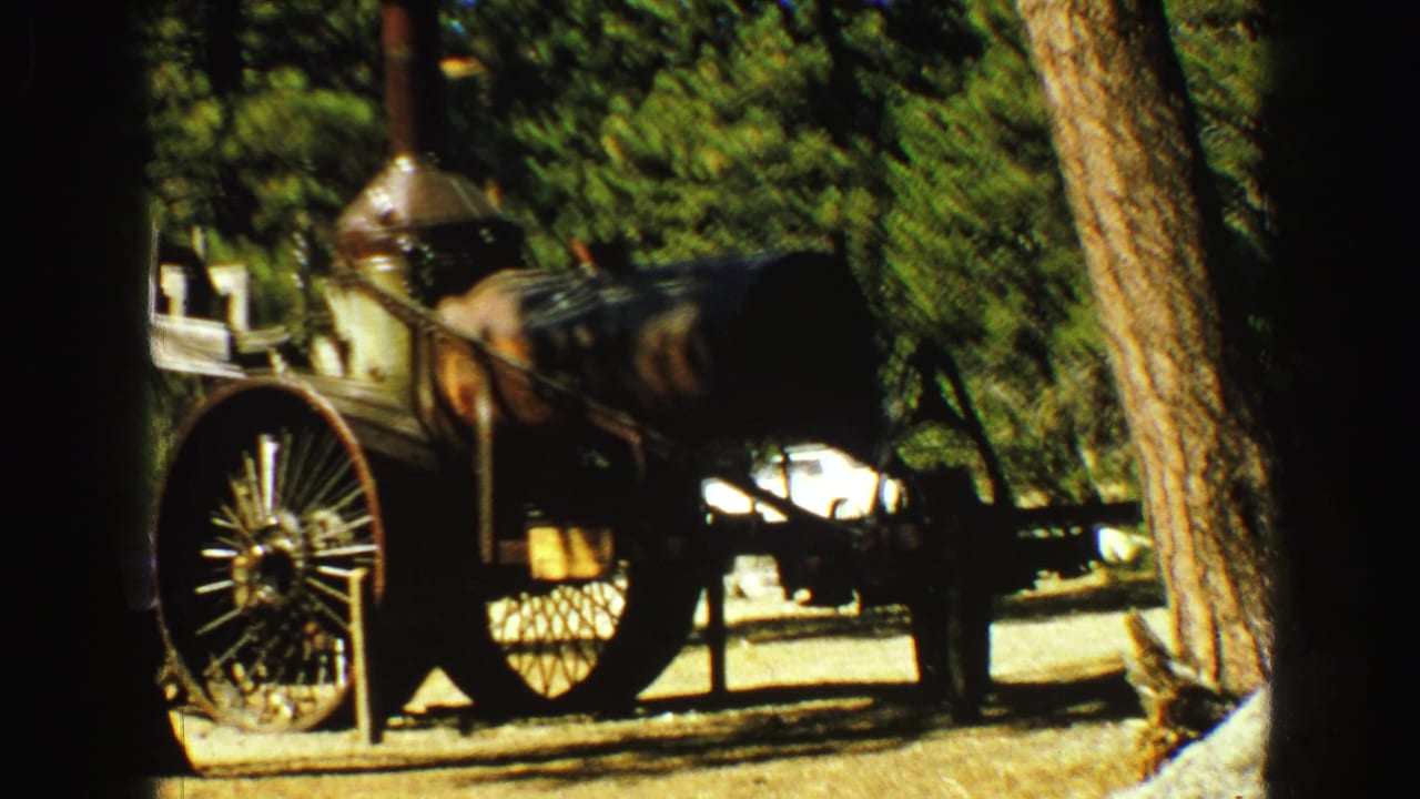 Closer view of a steam engine display with trees and railing.