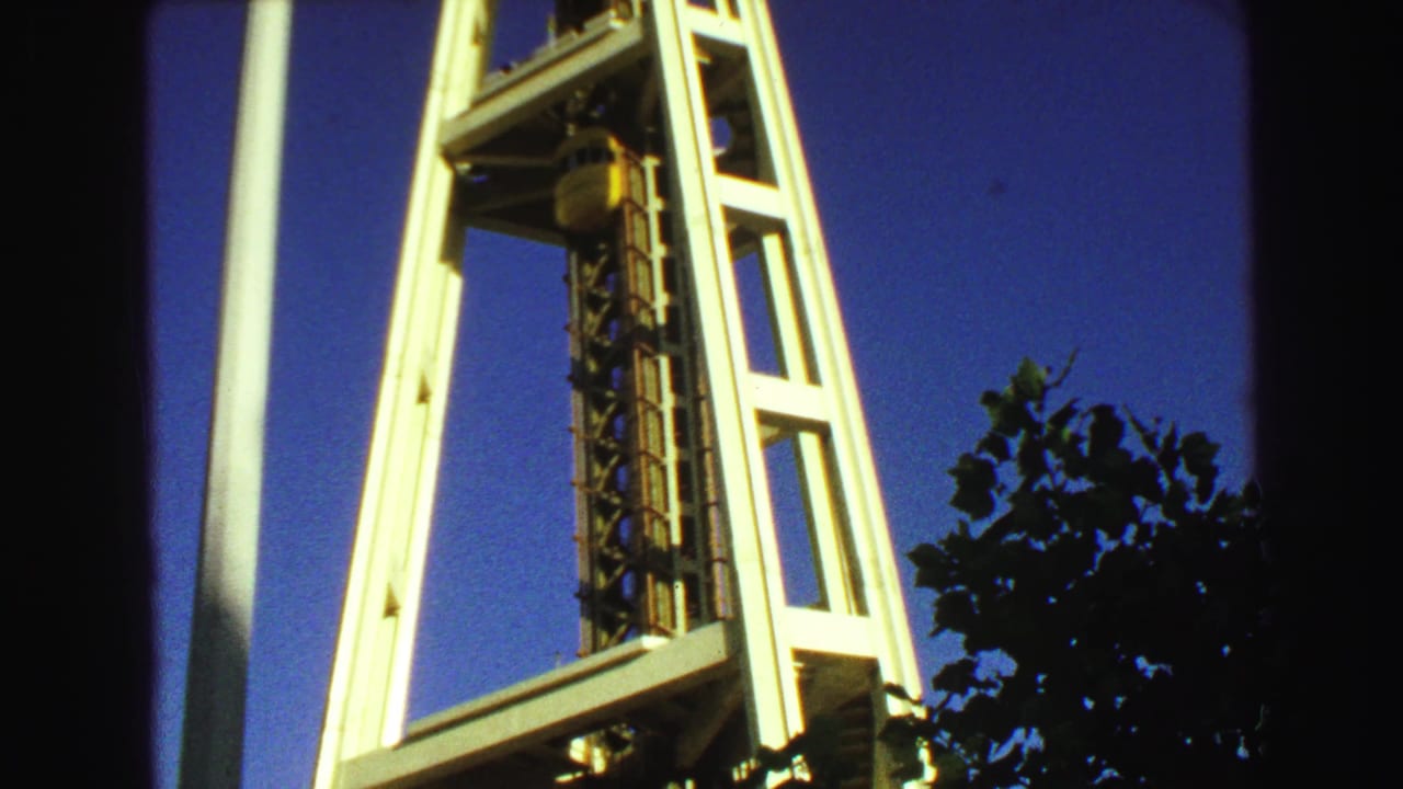 Low-angle view of Space Needle legs and elevator track against a dark blue sky.