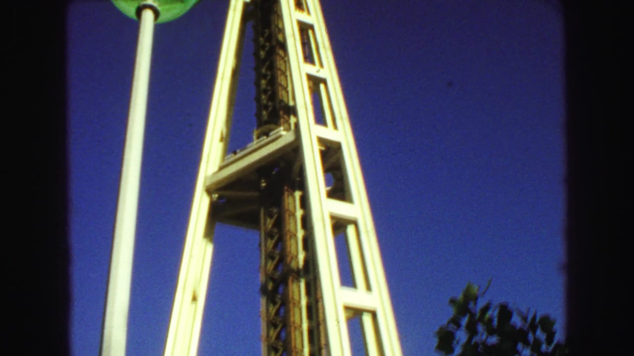Space Needle support structure with a green globe lamp near the top of the frame.