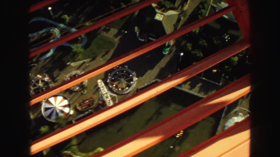 1968 Vancouver high-angle view through red structural beams, showing carnival rides and open grounds below.