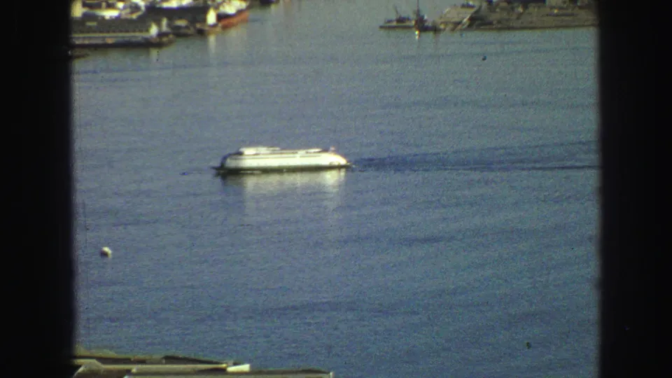 1968 Vancouver waterfront view showing a white boat crossing the water, with docks and other vessels in the distance.