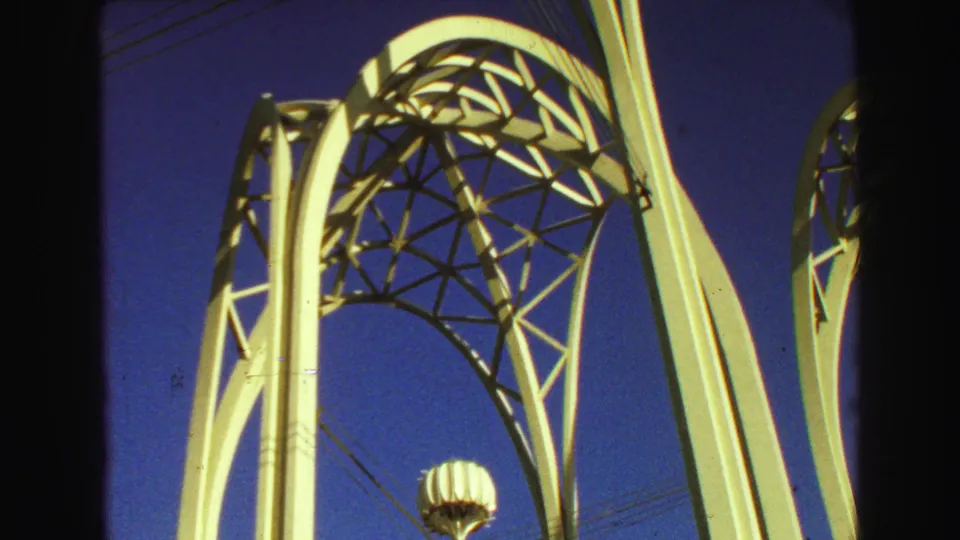 1968 Vancouver 8mm frame showing a white curved architectural structure and geometric latticework against a deep blue sky.