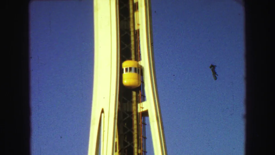 A yellow elevator car rides beside the upper portion of a white futuristic tower, with blue sky filling the background.