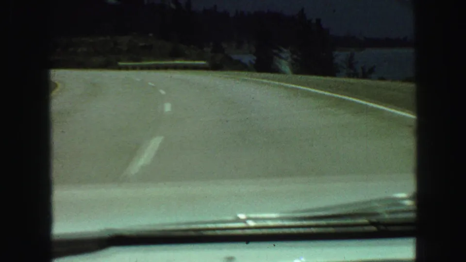 1968 8mm travel view from inside a car on a curving road near trees and water in the Vancouver, British Columbia area.