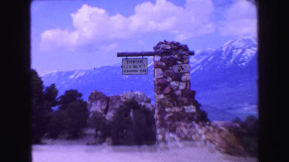Close 1968 home-movie view of the Geiger Lookout elevation sign on stonework against a mountain landscape.