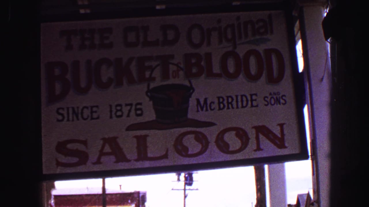 8mm frame of The Old Original Bucket of Blood Saloon sign, with McBride Sons text and a top-hat graphic near the storefront.