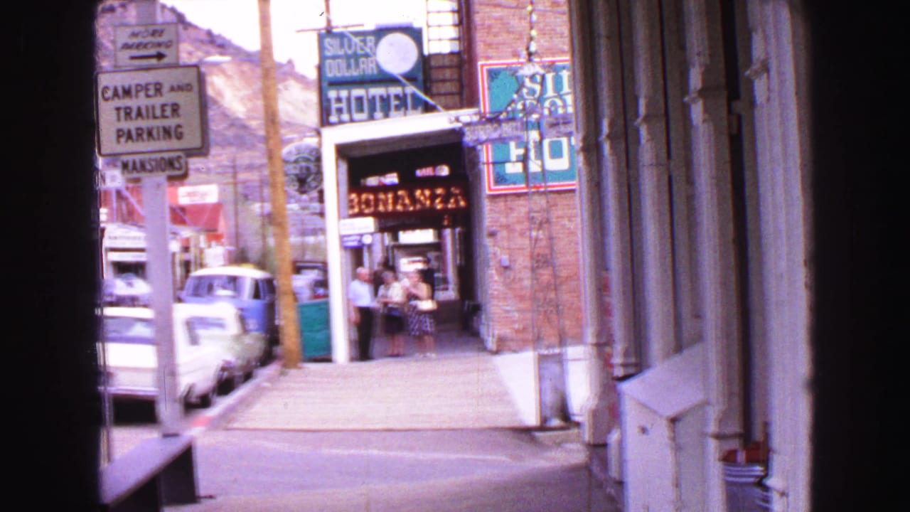 1968 Vancouver street view framed from inside, with Silver Dollar Hotel signage, Bonanza restaurant entrance, parked cars, and pedestrians.