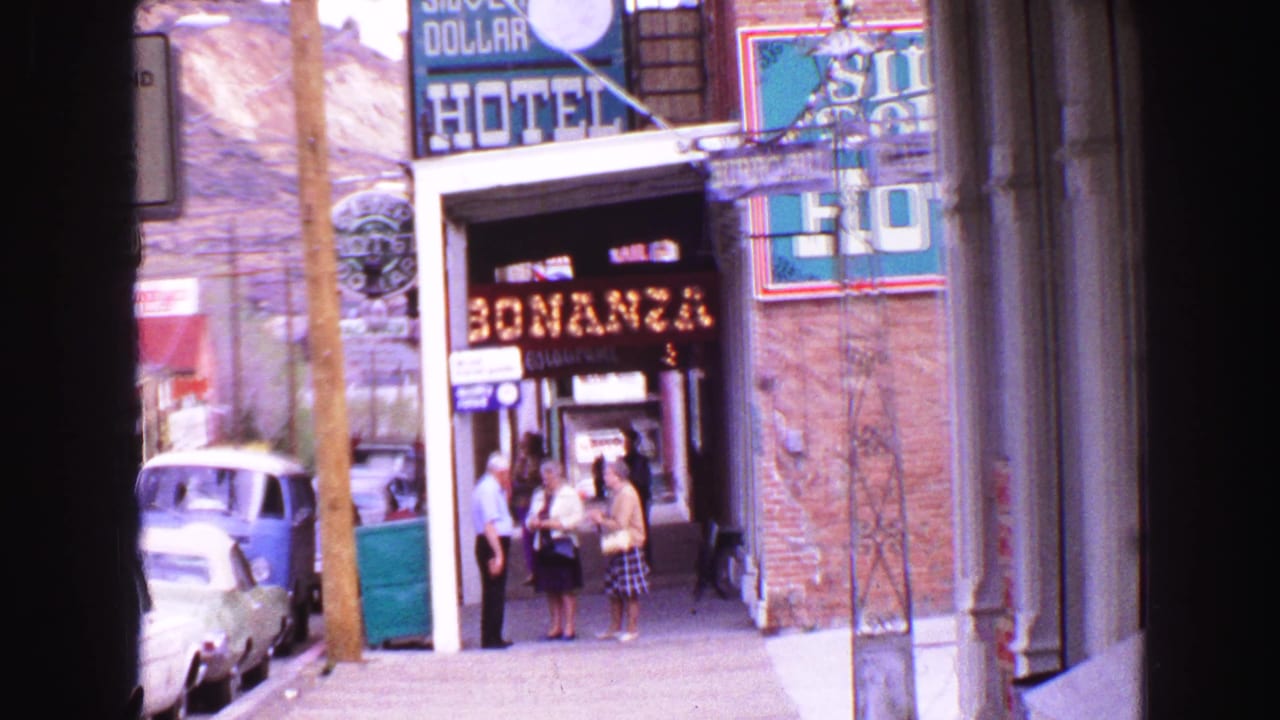 1968 Vancouver 8mm street frame with Bonanza restaurant signage, pedestrians at the entrance, a hotel sign, and mid-century parked cars.