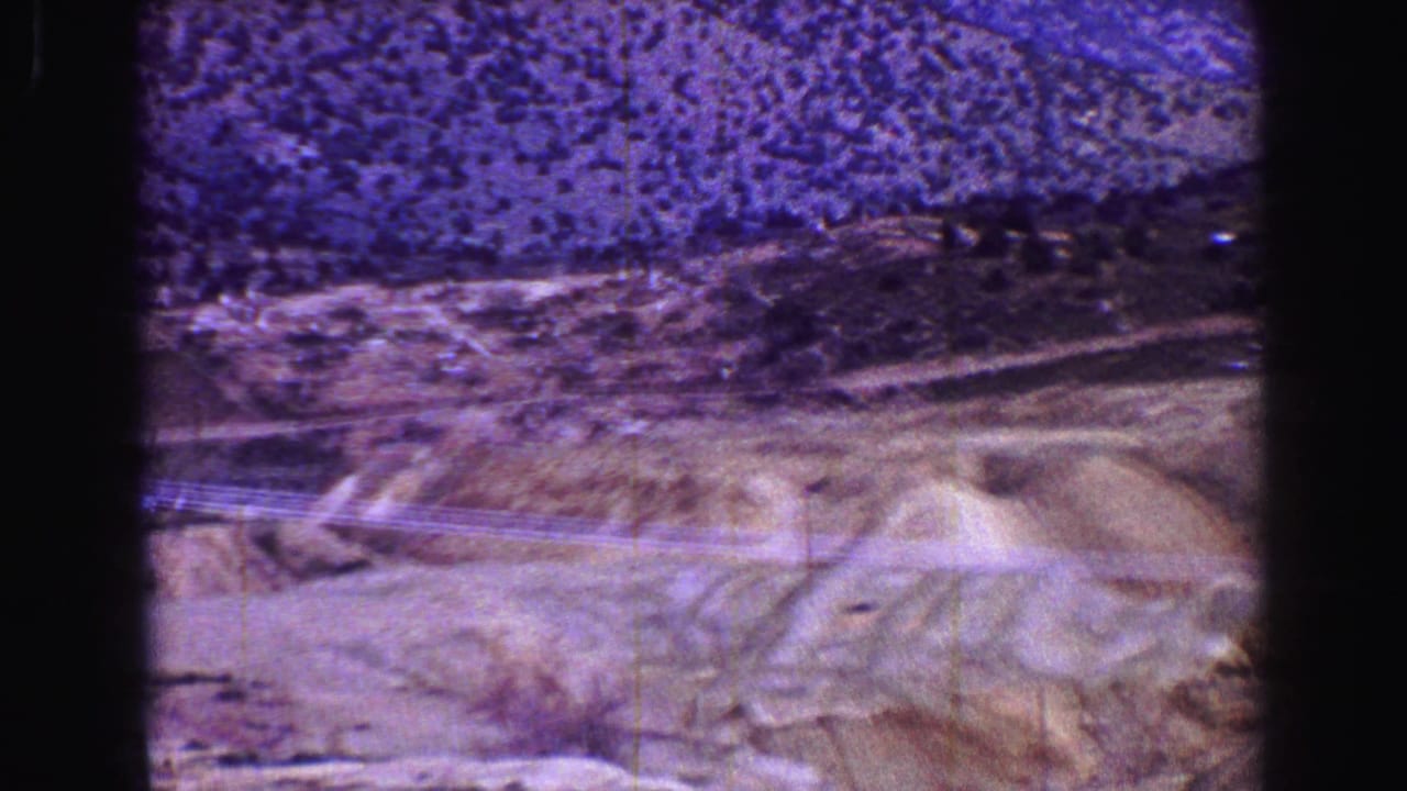 Arid hills and power lines crossing the frame beneath distant mountains.