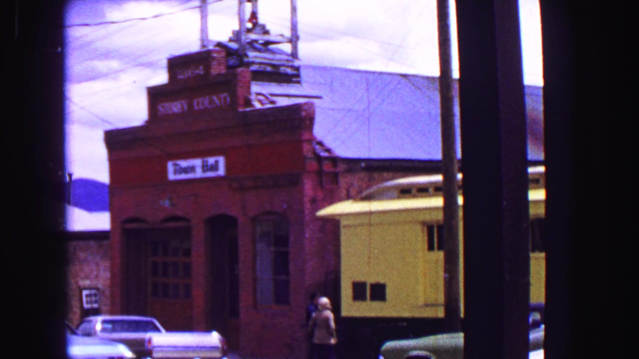 Red brick facade marked Stoney County Town Hall with a yellow rail car and parked cars nearby.