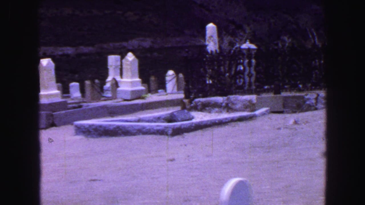 A 1968 Vancouver cemetery pan shows white headstones, grave borders, and an iron fence near shrubs and hillside rock.