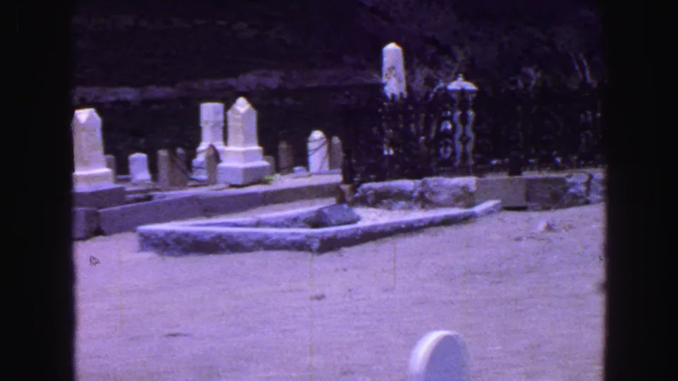 A 1968 Vancouver cemetery pan shows white headstones, grave borders, and an iron fence near shrubs and hillside rock.