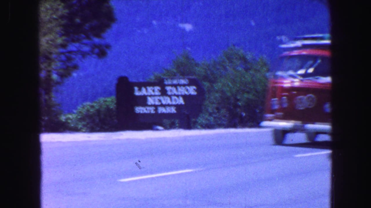 Red van passing a Lake Tahoe Nevada State Park sign beside a highway.