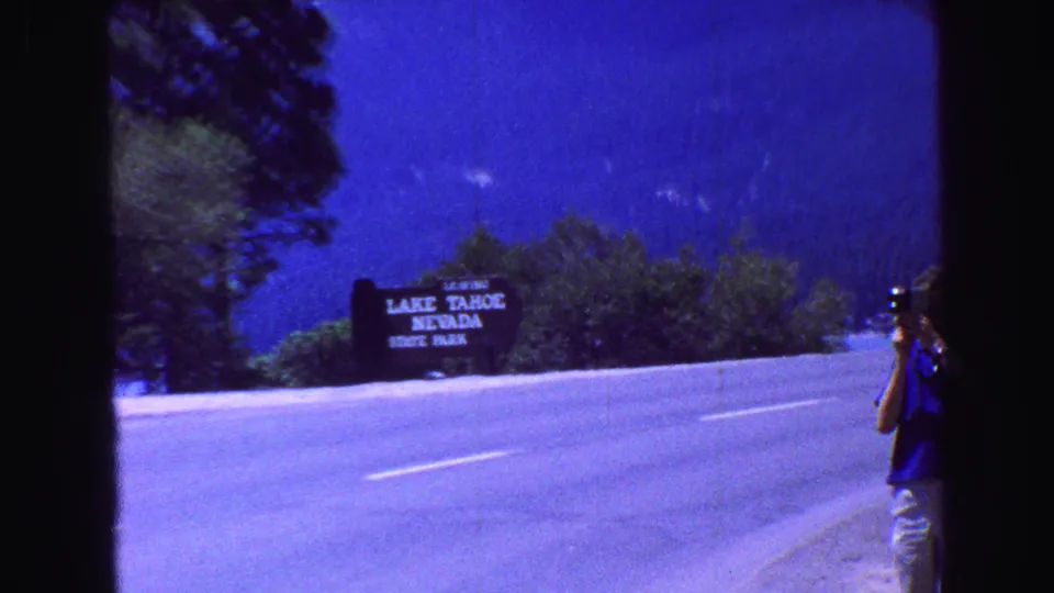 A person appears at the right edge while the Lake Tahoe Nevada State Park sign and highway remain in view.