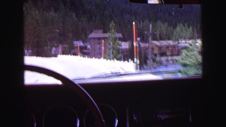 Windshield view from a car approaching a rustic lakeside lodge area in the 1968 Vancouver, BC home-movie clip.