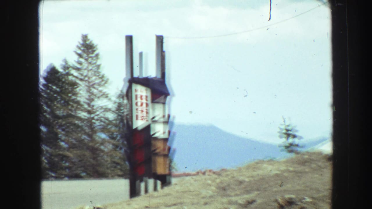 Roadside Mt Rose sign seen through a car windshield beside snowy mountain scenery.