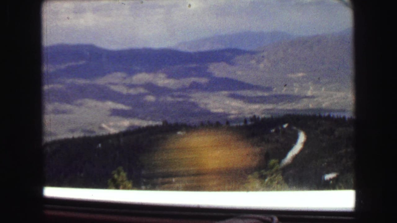 Mountain landscape seen through a car side window with dark window framing.