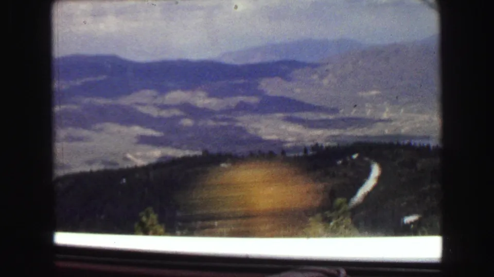 1968 8mm home-movie view of distant hills and a winding road seen through a car window near Vancouver, British Columbia.