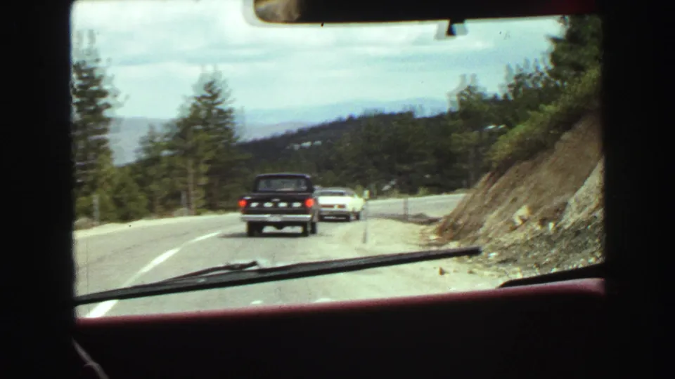 Vancouver-area 1968 road-trip frame with a black pickup and white car ahead on a two-lane mountain road.