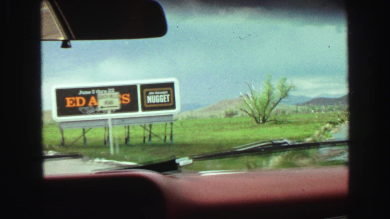 Car windshield view of a billboard for Ed Ames and Johnnie's Nugget.