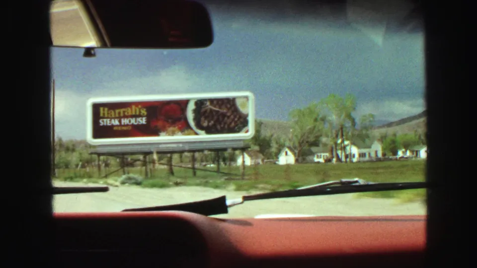 1968 car-interior view near Vancouver with a red dashboard and a Harrah's Steak House billboard along a rural roadside.
