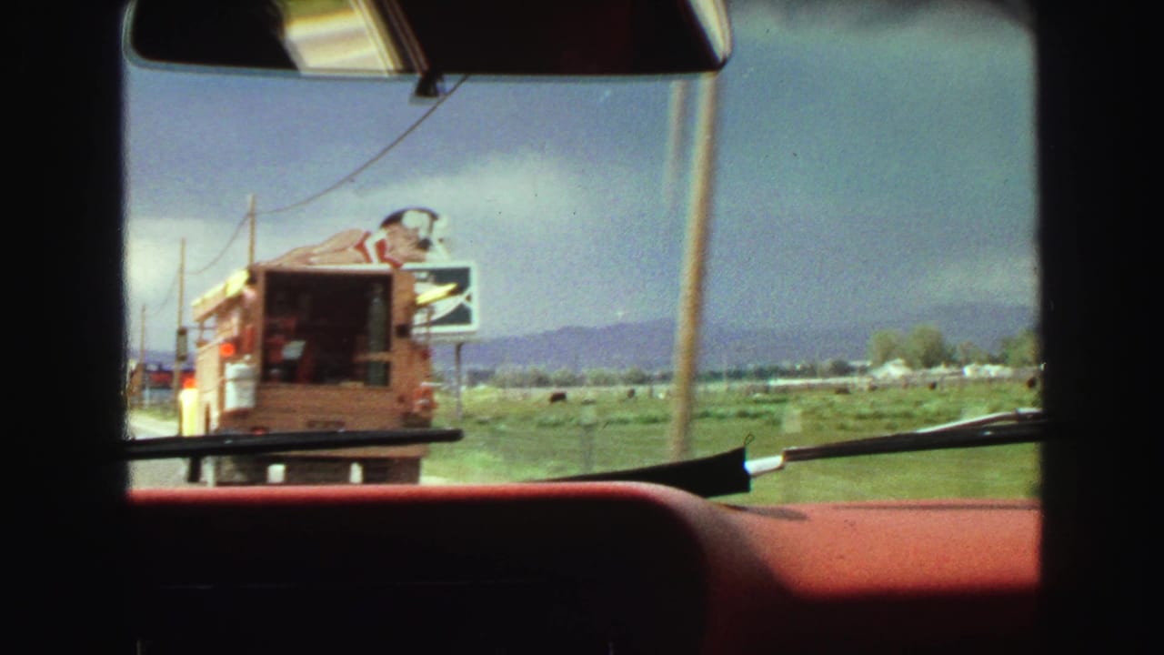 View through a car windshield with a food truck ahead and roadside signage beyond.