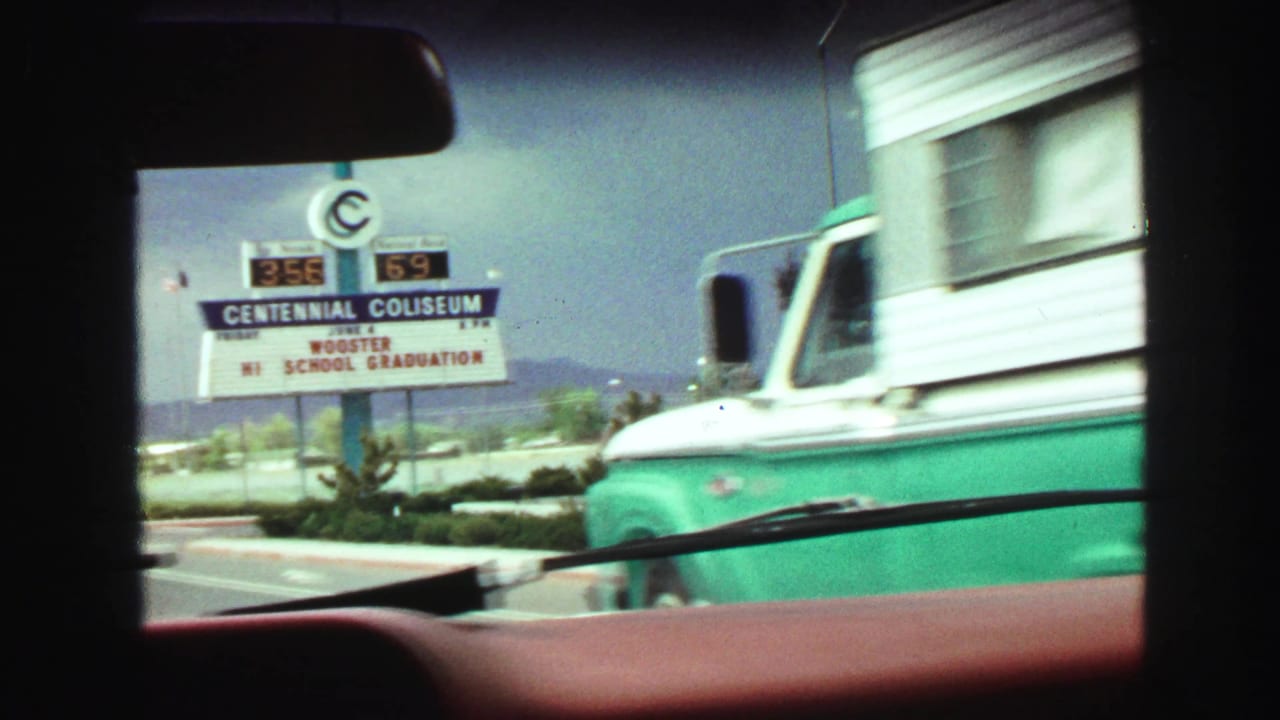 Centennial Coliseum sign beside the road with a green and white vehicle passing nearby.