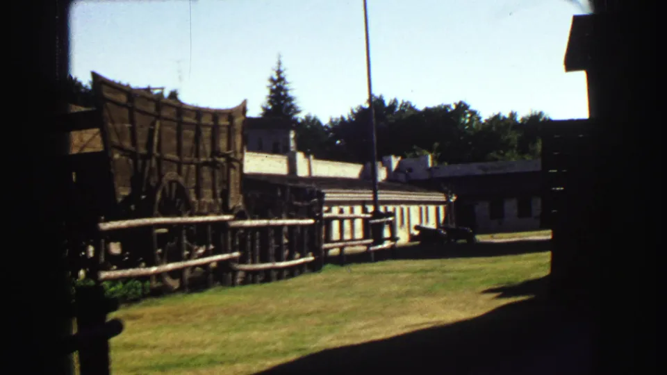 A final 1968 Vancouver view holds on the wagon display, low buildings, lawn, fence, and trees under bright daylight.