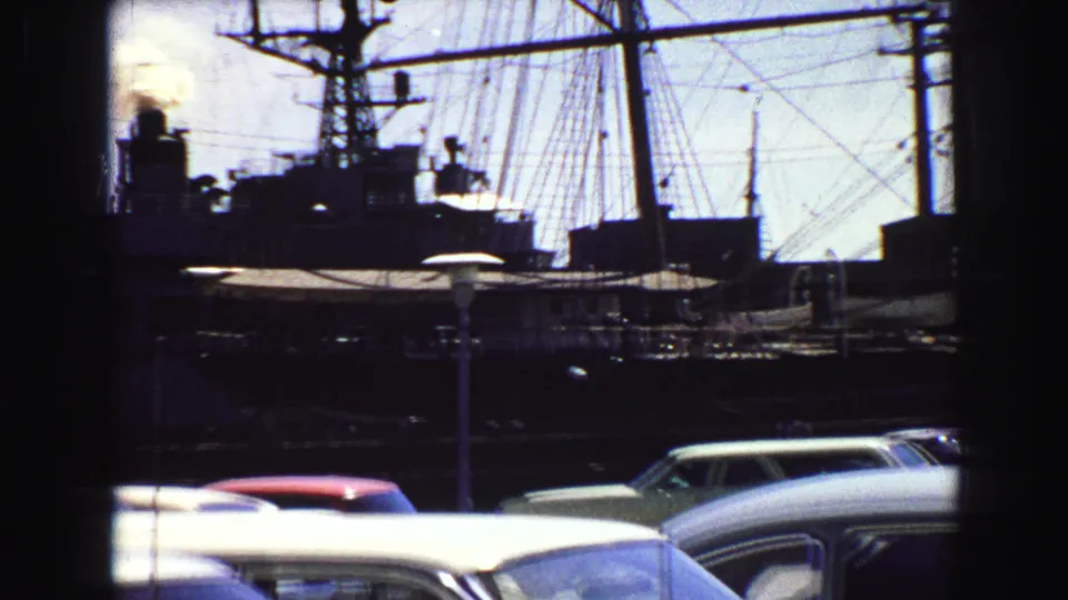 1968 Vancouver waterfront view with ship rigging, a stack emitting smoke, and mid-century cars in the foreground.