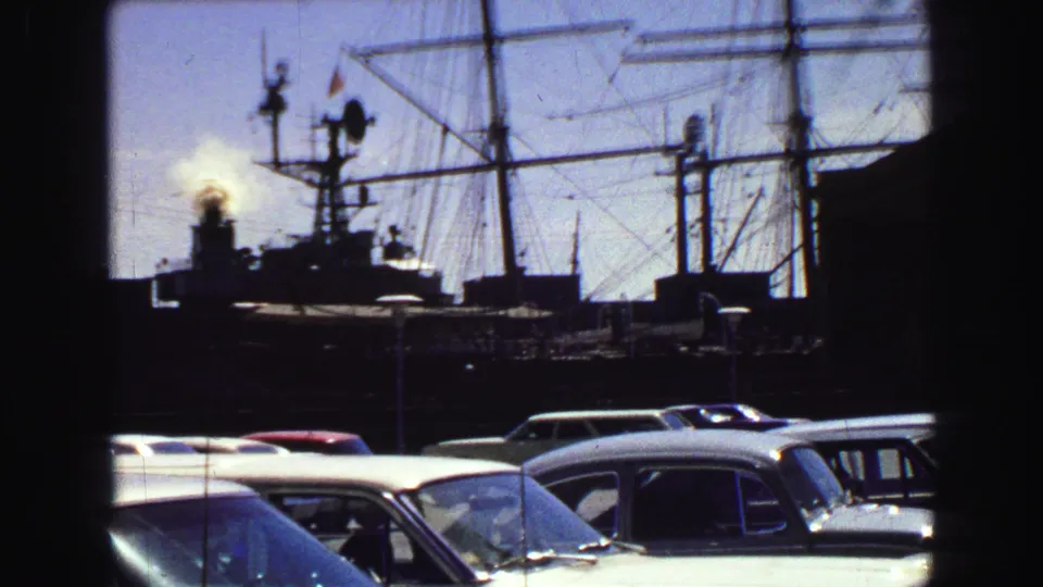 Vancouver 1968 frame with foreground parked cars, tall ship rigging, and a smoking stack silhouetted against the sky.