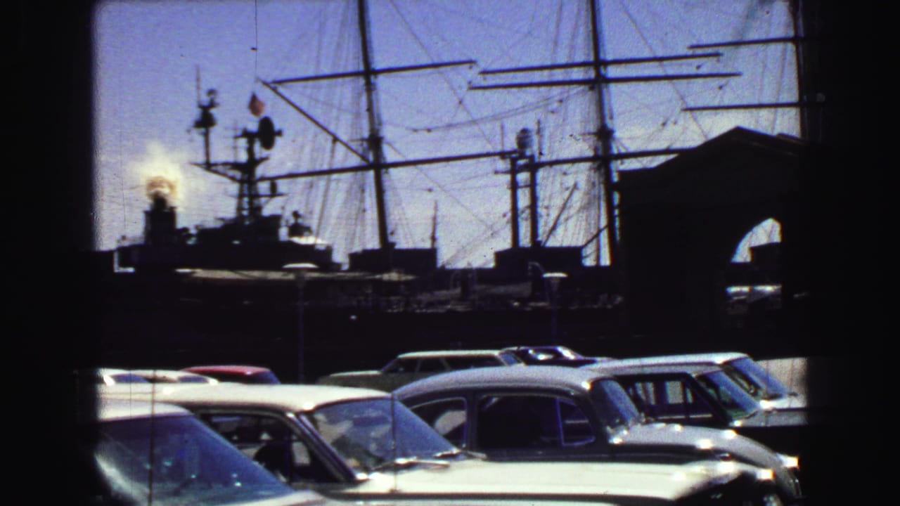 1968 Vancouver harbor view from a parking area, with classic cars in front of masts, a smoking stack, and an OPEN TO PUBLIC sign.