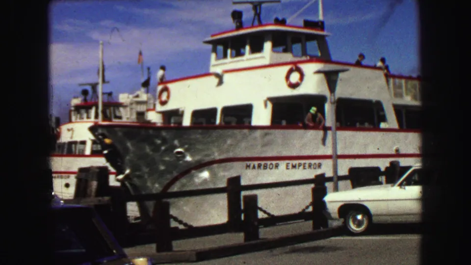 The Harbor Emperor passenger ferry at a Vancouver dock in 1968, with passengers visible on deck, pier railings, and a white car nearby.
