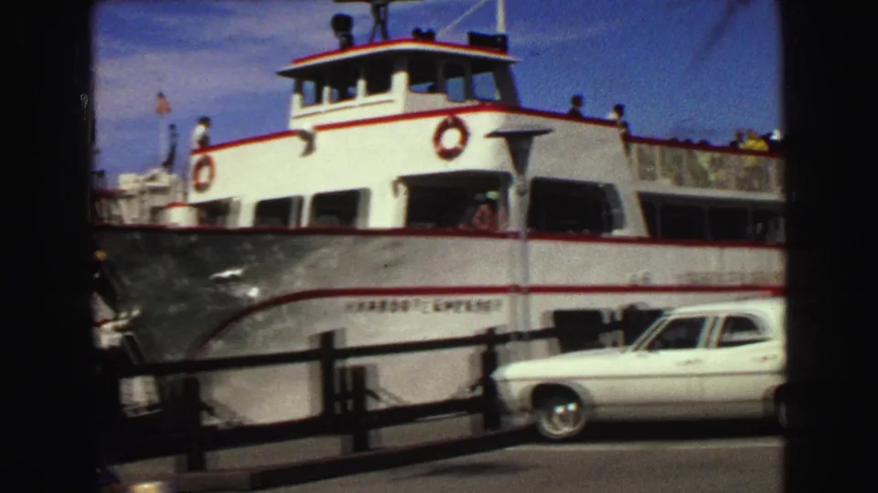 1968 Vancouver dock scene with the Harbor Emperor ferry, visible passengers, pier railings, and a white sedan passing or parked nearby.
