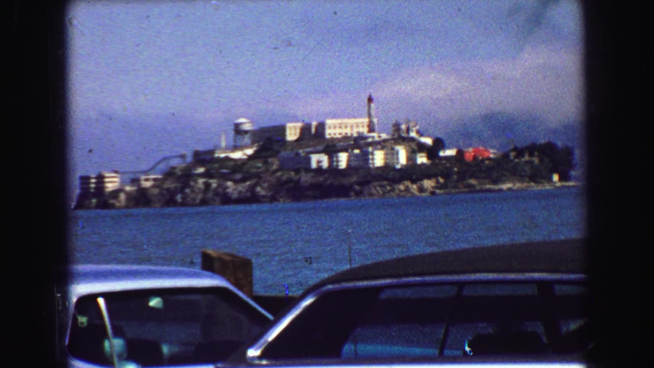 Closer view of Alcatraz across water with cars along the lower frame.