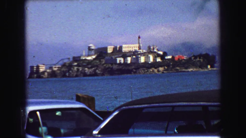 Alcatraz Island fills more of the frame across San Francisco Bay, with parked cars partly visible at the waterfront edge.
