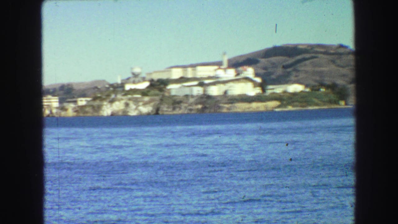 Distant Alcatraz buildings and water tower beyond rippled bay water.