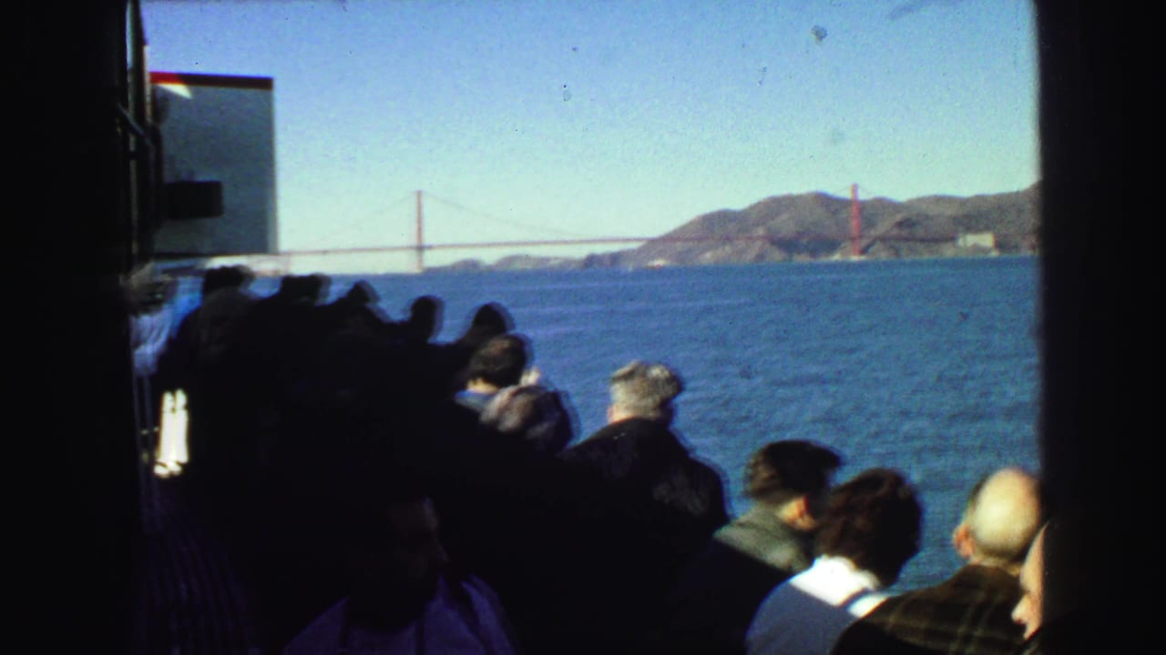 1968 8mm frame of male passengers on a boat viewing the Golden Gate Bridge across San Francisco Bay.