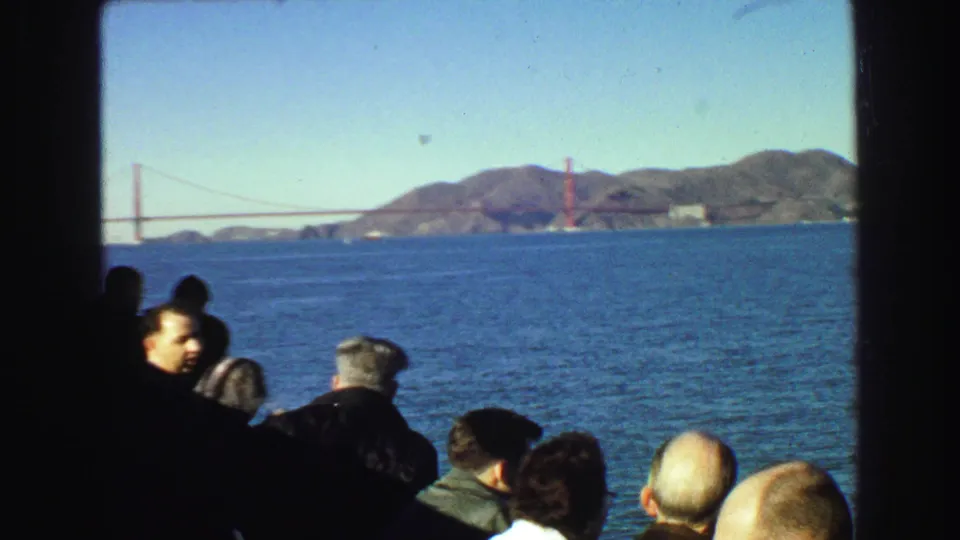 Men aboard a passenger boat look out over San Francisco Bay toward the Golden Gate Bridge in a 1968 home-movie frame.