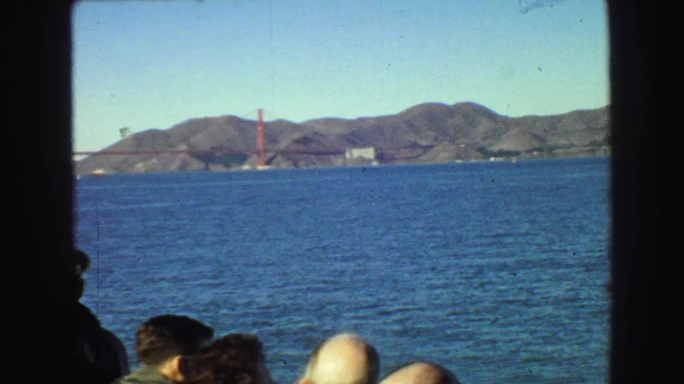 1968 8mm view from a boat across San Francisco Bay, with passengers low in frame and the Golden Gate Bridge beyond.