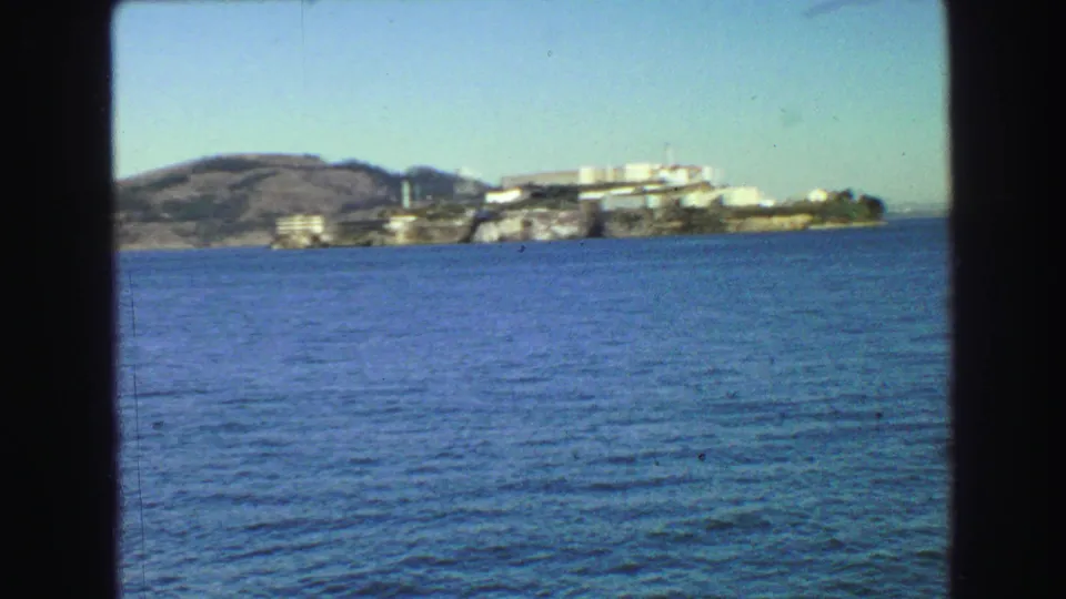 1968 home-movie view near Vancouver showing rippled bay water and hillside waterfront buildings in the distance.